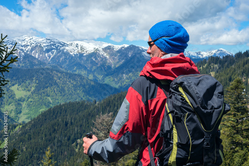 Confident man traveler in sunglasses stands in the mountains