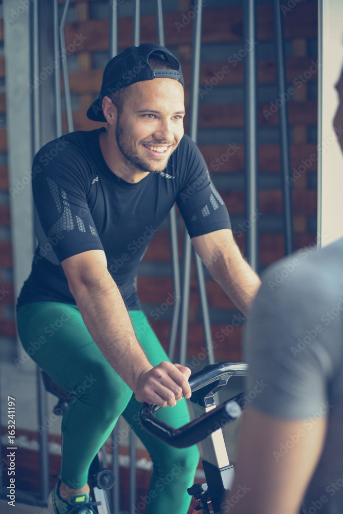 Young man exercise on stationary bikes in fitness class. Man workout in gym. Exercise on elliptical machine. Man personal trainer. Young man exercise on stationary bikes in fitness class. Man workout in gym. Exercise on elliptical machine. Man personal trainer.