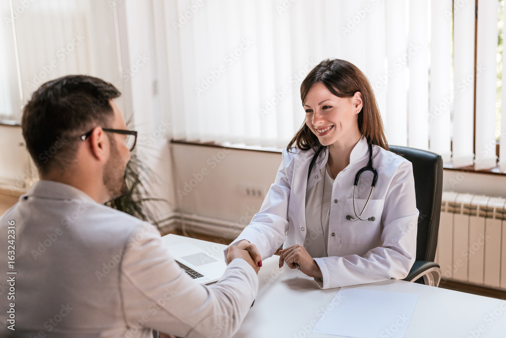 Smiling female doctor at the clinic giving an handshake to her patient Smiling female doctor at the clinic giving an handshake to her patient