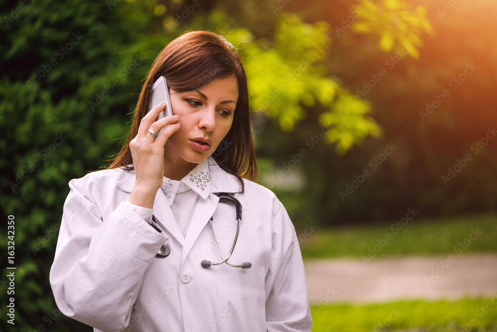 Young female doctor talking on the phone outdoors Young female doctor talking on the phone outdoors