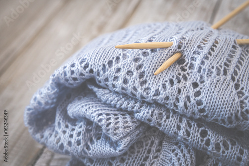 Detail of woven handicraft knit woolen design texture and knitting bamboo needle. Toned retro. Rustic wooden background.