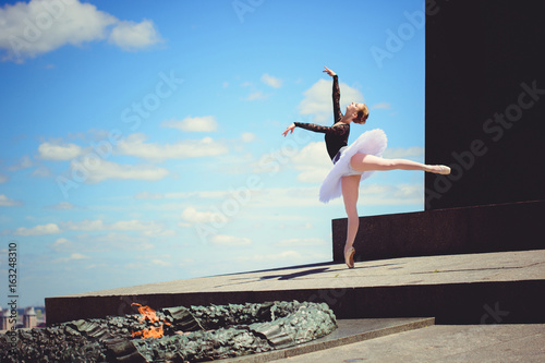 Young ballerina in ballet costume dancing in city park  on stairs feeling breath of big city life and freedom