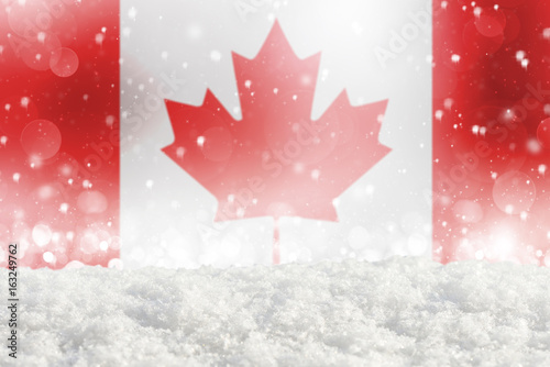 Defocused Canada flag as a winter Christmas background with falling snow, snowdrift and bokeh