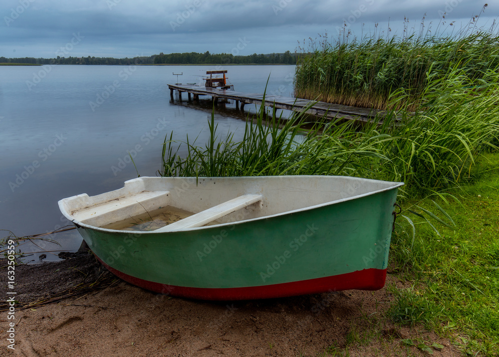 Fisherman boat on the beach during rain in the evening on Masuria, Poland