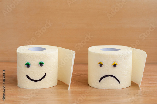 Toilet paper with googly eyes on wooden background.