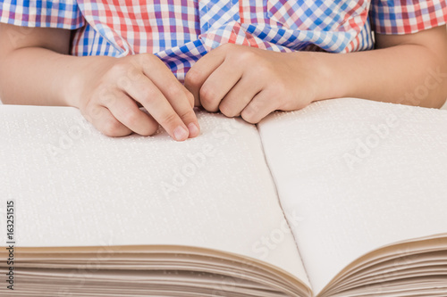 The blind boy is reading a book written on Braille. © fusssergei