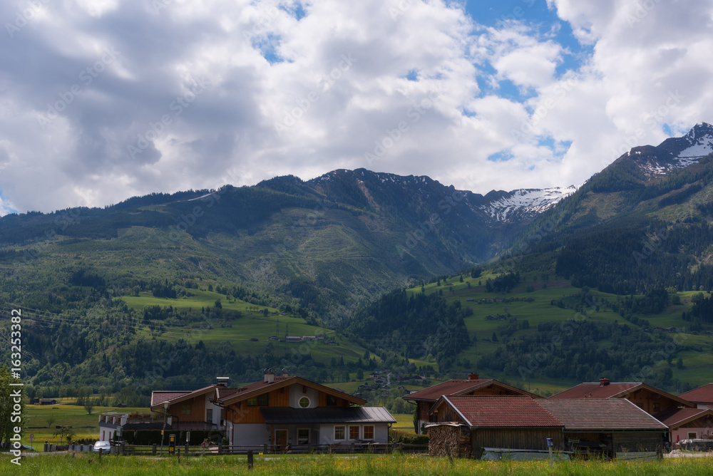 Idyllic landscape in the Alps in springtime with traditional mountain chalet and fresh green mountain pastures with blooming flowers on a beautiful sunny day. Austria, Europe.