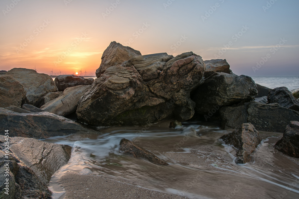 Stones on the beach and windmills, dawn