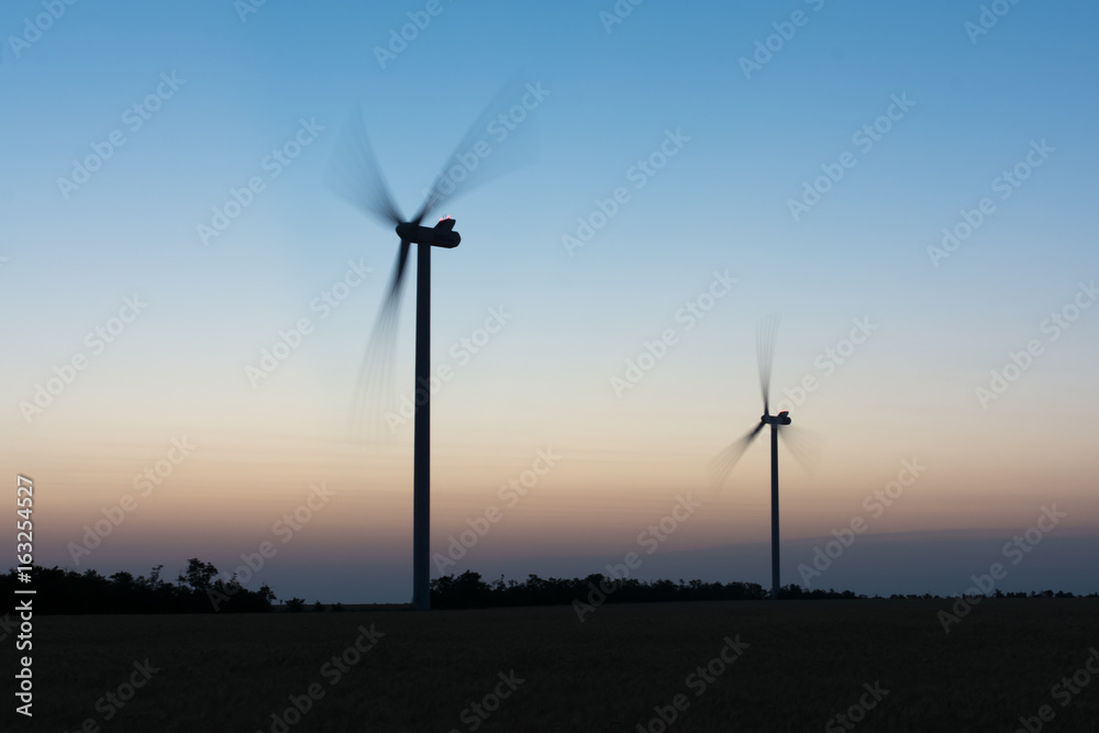 Obraz premium Wind turbines at sunset at dusk in a wheat field