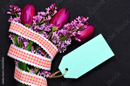Fototapeta Naklejka Na Ścianę i Meble -  Bunch of flowers wrapped with ribbon and light blue tag
