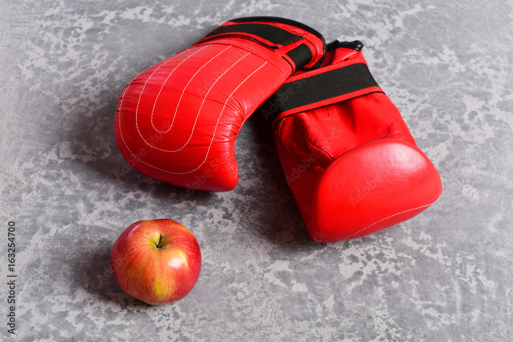 Sport equipment and fruit on grey texture background. Boxing gloves