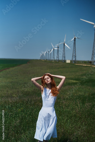 Foto Beautiful young woman in a field near a windmill, summer, sun