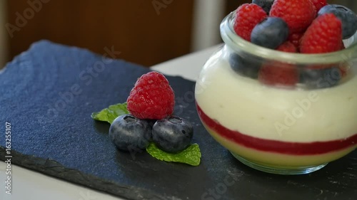 Female hands are adorned with berries. Hand putting Strawberry in Yogurt, close up. photo