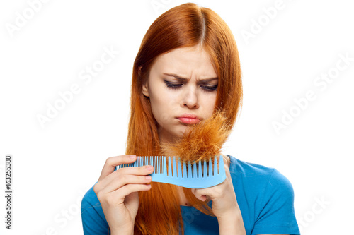 Beautiful young woman on white isolated background holds a comb