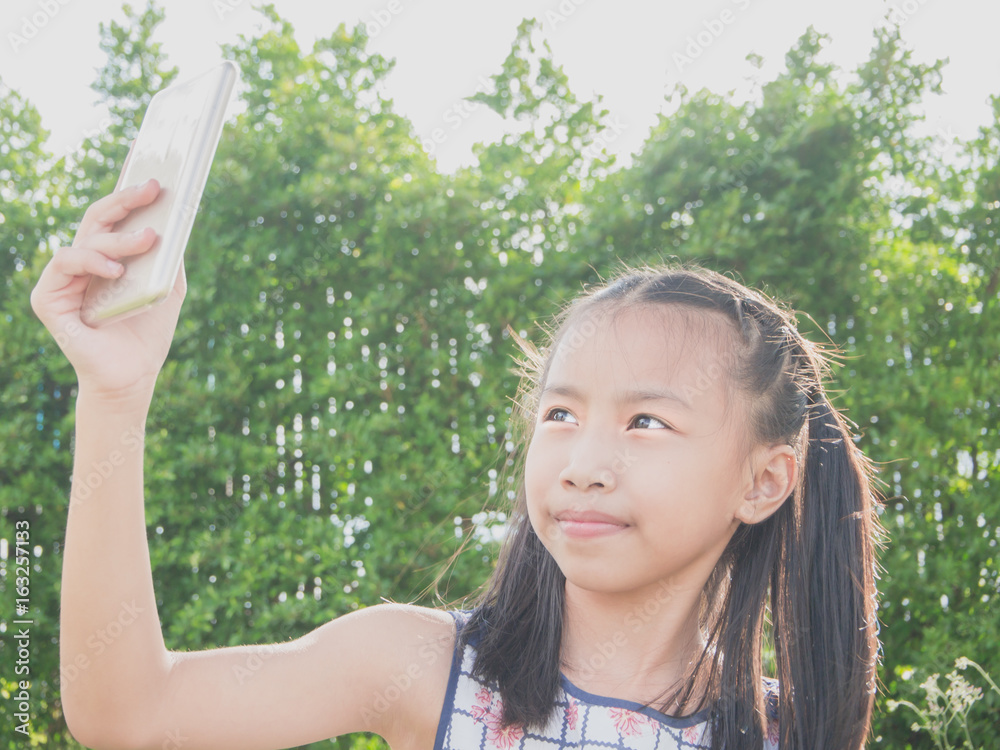 Happy child taking a selfie with smartphone in the park. Happy child taking a selfie with smartphone in the park.