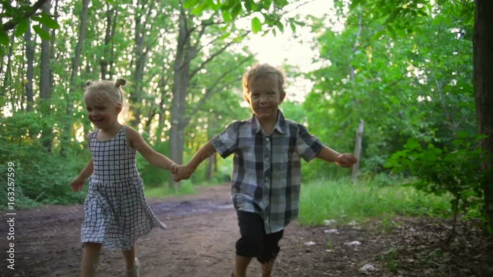 Small couple boy girl holding hands running smiling sunny park rapid slow motion Small couple boy girl holding hands running smiling sunny park rapid slow motion