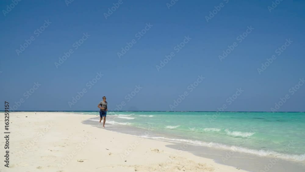 Man running along beach. Fitness sports runner man jogging on beach. Handsome young fit sporty male athlete running outside on beautiful beach training. 4K video. Man running along beach. Fitness sports runner man jogging on beach. Handsome young fit sporty male athlete running outside on beautiful beach training. 4K video.