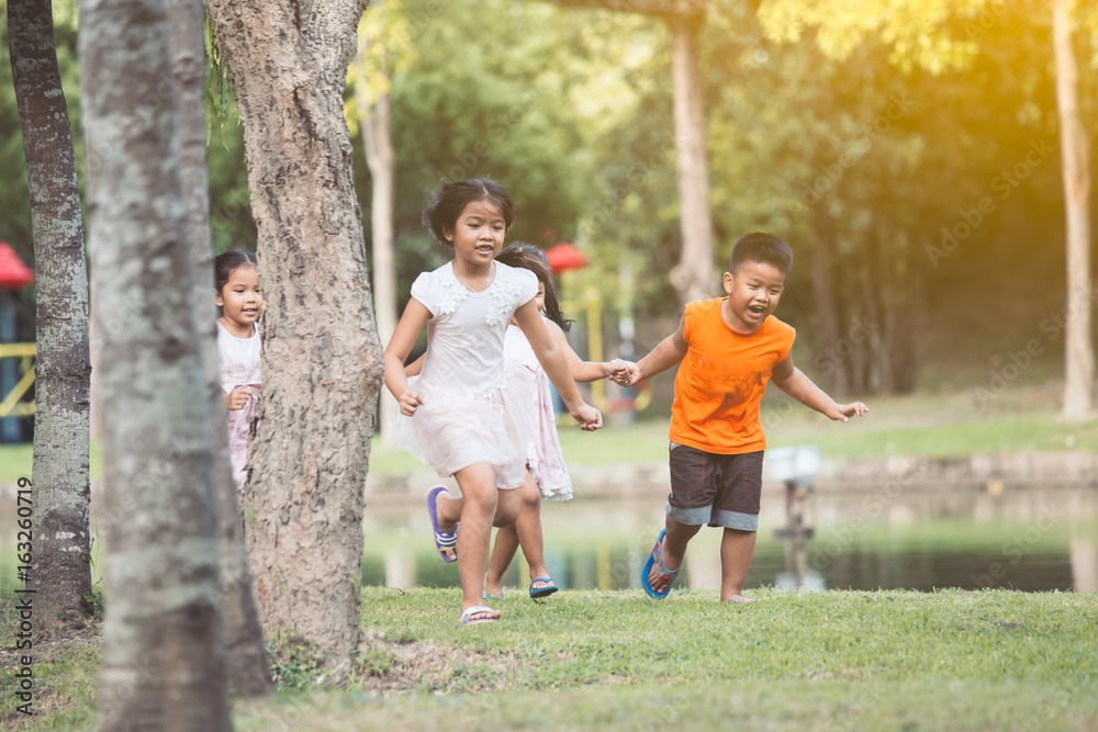 Fototapeta premium Asian children having fun to run and play together in the park in vintage color tone