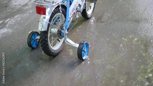 A child riding a children's bike through the puddles