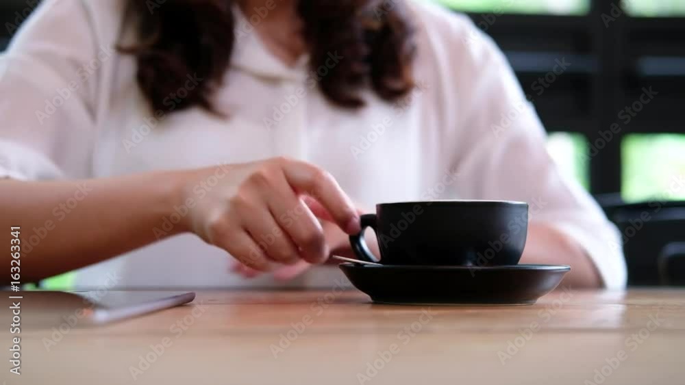 A woman receiving a black coffee cup from waiter and drinking it in coffee shop A woman receiving a black coffee cup from waiter and drinking it in coffee shop