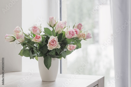 pink roses in vase on background window