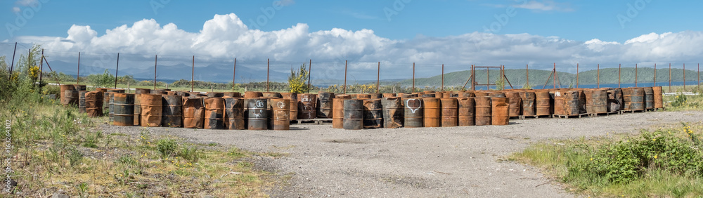 Rusty fuel and oil casks stored at an fence Rusty fuel and oil casks stored at an fence