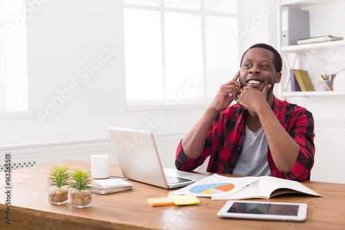 Young black businessman call mobile phone in modern white office