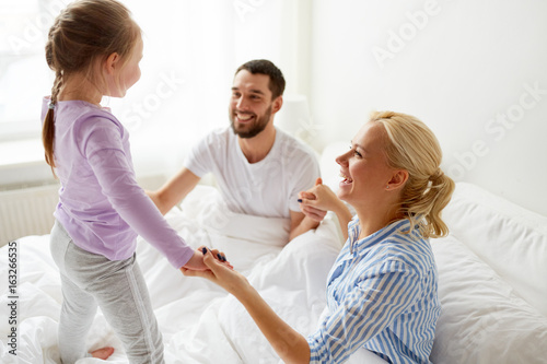 happy family holding hands in bed at home