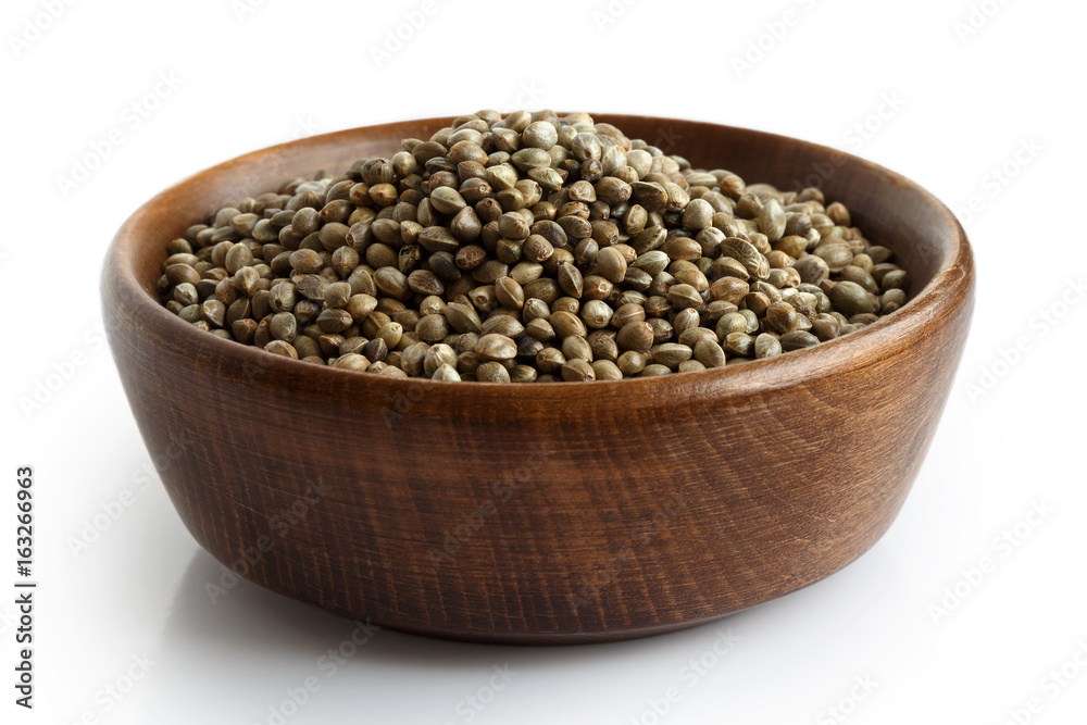 Hemp seeds in dark wooden bowl isolated on white. Hemp seeds in dark wooden bowl isolated on white.