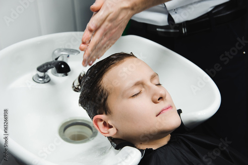 a boy is washed by the hairdresser in the barbershop