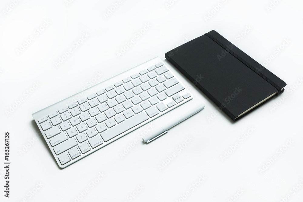 Modern aluminum computer keyboard and black cover notebook isolated on white background