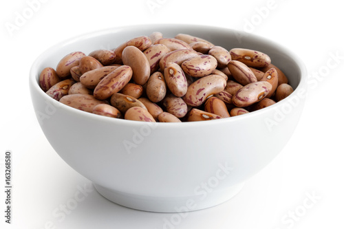 Dry pinto beans in white ceramic bowl isolated on white.