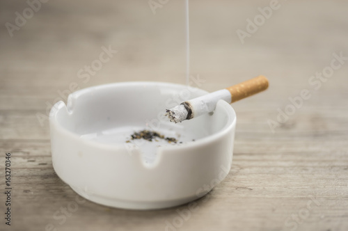 Lit cigarette burning in ashtray close up