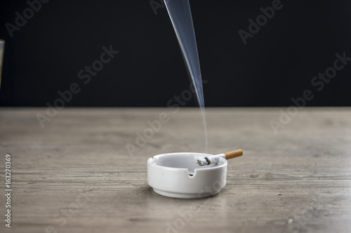Lit cigarette burning in ashtray close up