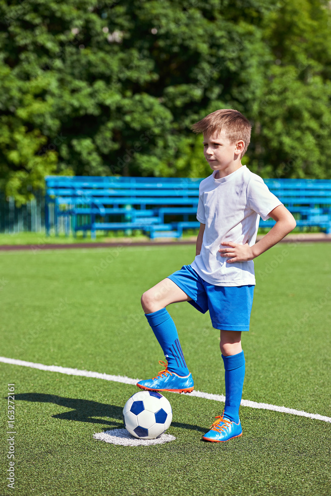 Boy soccer in football boots with ball on grass