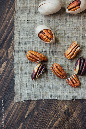 Pecan nuts on piece of cloth over wooden table.