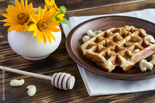 Wafflers with nuts and honey in the brown plate on the wooden background