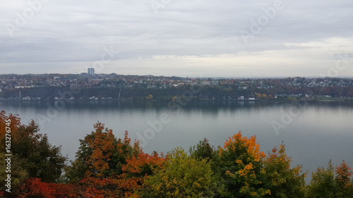 River near Quebec City, autumn trees covered with red, yellow and green foliage, cityscape on the other bank, Canada