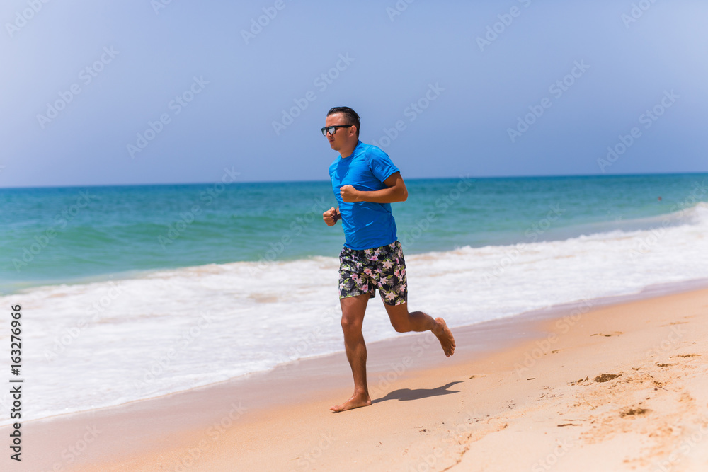 Man running on sunny beach near ocean