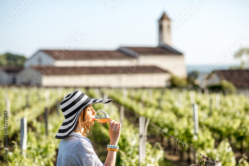 Fototapeta Young woman tasting wine standing outdoors on the vineyard in Bordeaux region du