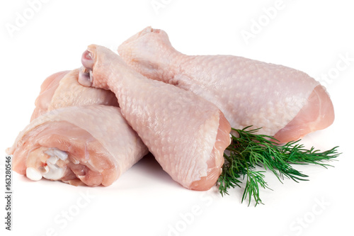 Three raw chicken drumsticks with a sprig of dill isolated on white background