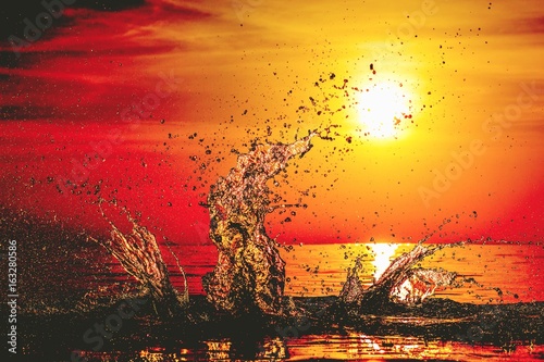 Billede på lærred Water splash at sunset with dark orange, red and yellow light at freeze motion,