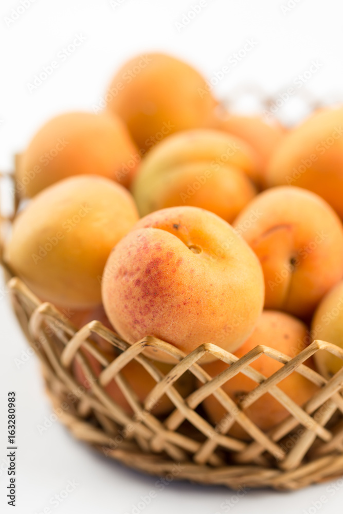 Fresh apricot in the wicker bowl above white background. Fresh apricot in the wicker bowl above white background.