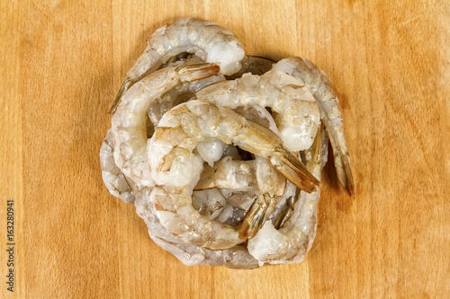 Raw peeled Shrimps or Prawns On wooden board. Background. Top View. Close Up. photo