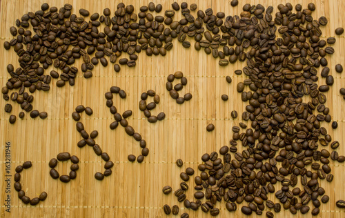 a scattering of roasted coffee beans and the words "Coffee" on a bamboo mat, background