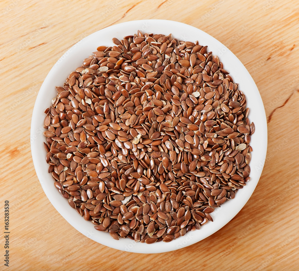 Flax seeds on a white plate, on an old wooden background. Flax seeds on a white plate, on an old wooden background.