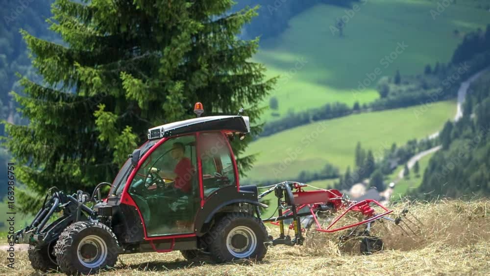 Farmers are preparing hay on steep hills. There are mountains and valleys in the background. Farmers are preparing hay on steep hills. There are mountains and valleys in the background.