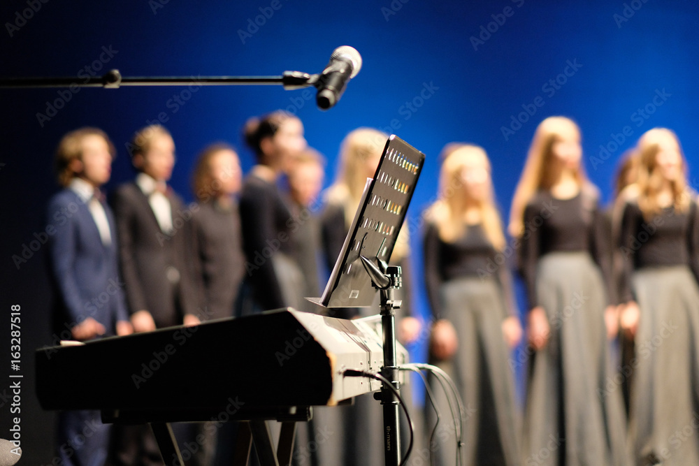 Naklejka premium Mikrofon i muzyka stoją przed fortepianami elektrycznymi na scenie teatru