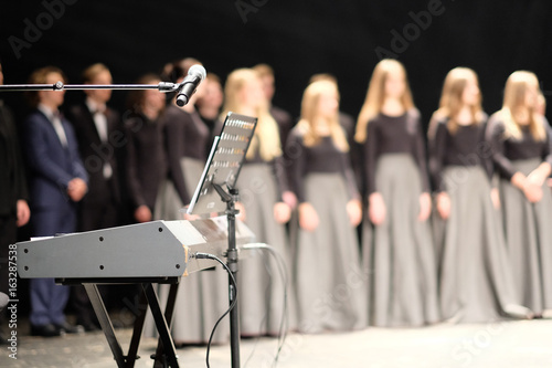 Microphone and music stand in front of electric pianos on the stage of the theater