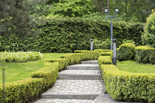 Cobbled stepped trail in a beautiful park framed by sheared shrubs